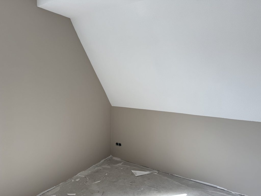 Kamer met een schuine wand, strak gesausd in wit en een warme grijstint
