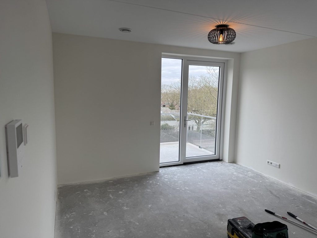 Lege kamer met gladde lichte wanden en openslaande deuren naar het balkon